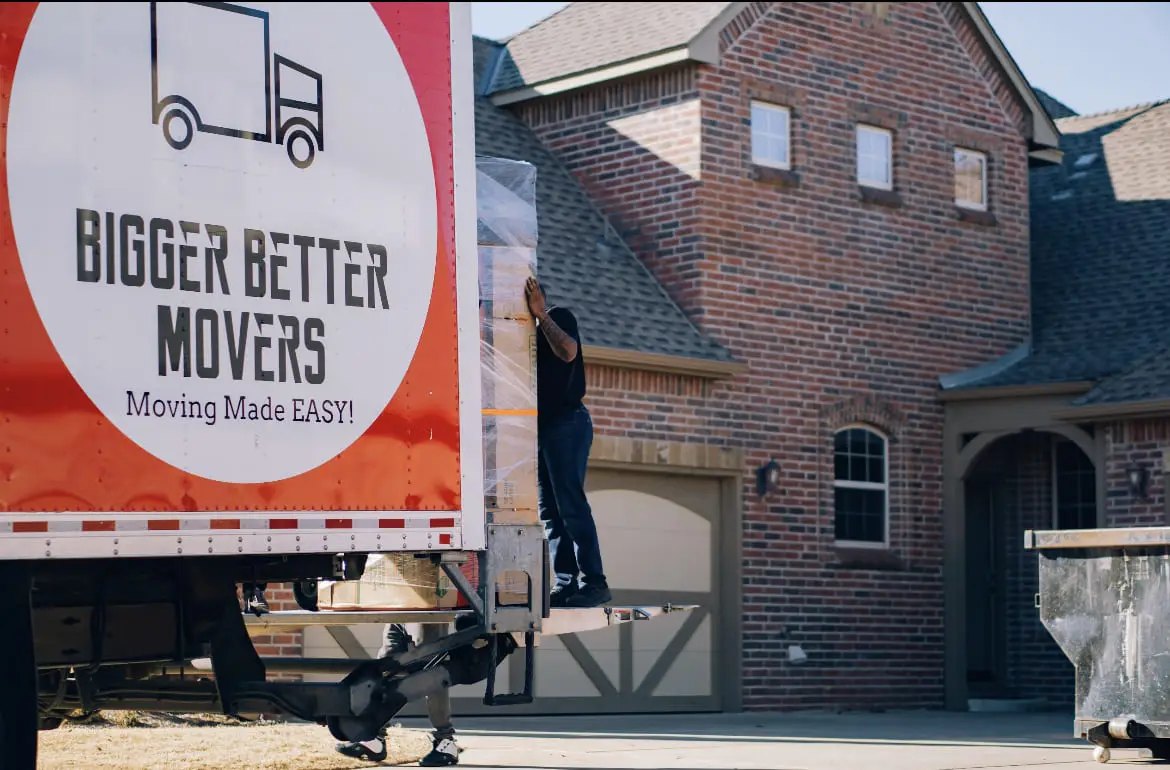 Bigger Better Movers crew using a liftgate outside a brick home in Oklahoma.